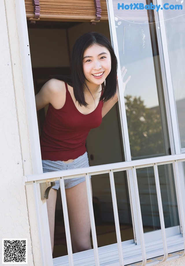 A woman standing on a balcony looking out of a window.