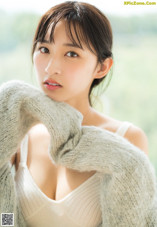 A woman in a white sweater is posing for a picture.