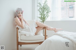 A woman sitting on a chair in a white room.