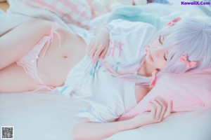 A woman laying on a bed in a white and pink outfit.