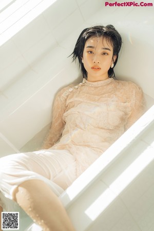 A woman laying on top of a table with her hand on her chin.