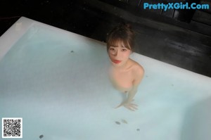 A naked asian woman sitting on a window sill.