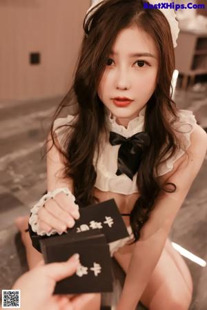 A woman in a black and white lingerie sitting on a table.