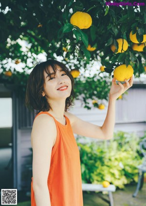 A woman in an orange dress posing for a magazine.