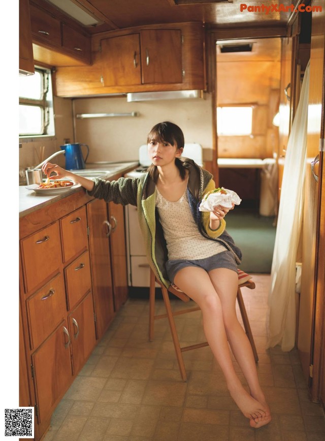 A woman sitting on a chair in a kitchen.