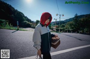 A woman in a red riding hoodie is walking across a bridge.