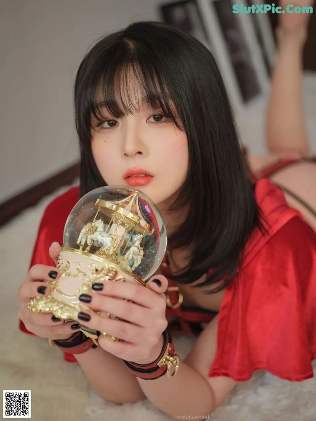 A woman in a red dress holding a crystal ball.