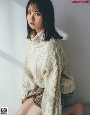 A woman with long black hair wearing a gray sweater.