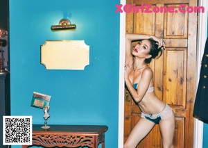 A woman in a blue bra and panties posing in front of a door.