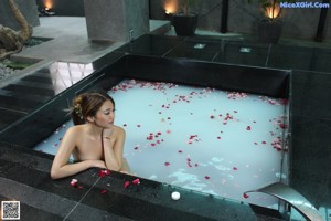 A naked woman sitting on the edge of a swimming pool.
