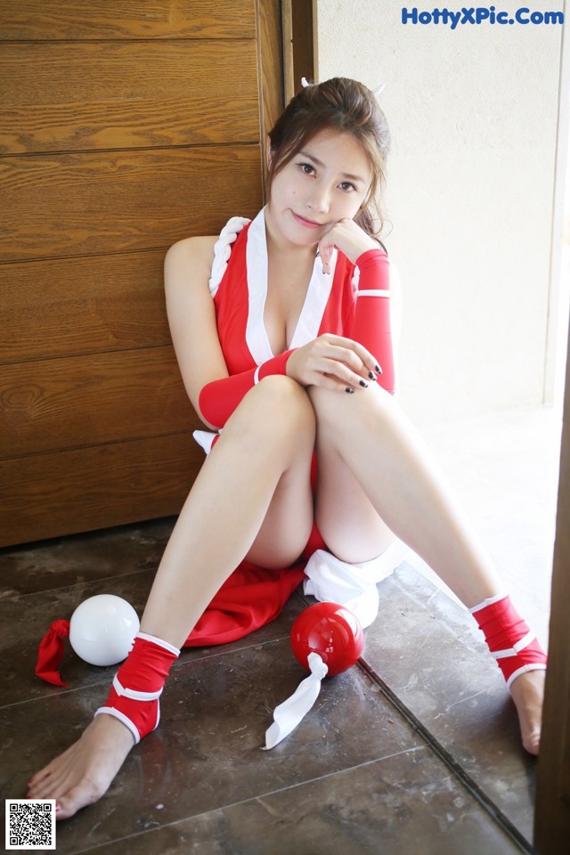 A woman in a red and white outfit sitting on the floor.