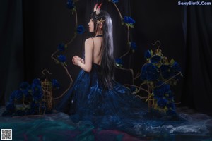 A woman in a blue dress sitting on a chair.