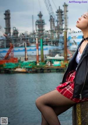 A woman in a leather jacket and plaid skirt posing for a picture.
