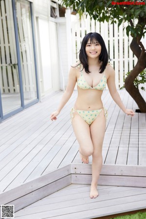 A woman in a white bikini sitting on the floor.