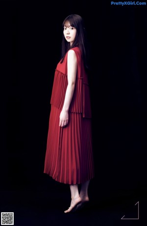 A woman in a red dress sitting on the ground.