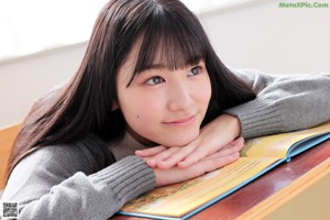 A young woman wearing a gray sweater and a red bow tie.