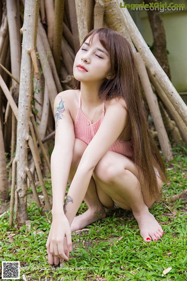 A woman in a pink bikini sitting on the ground.