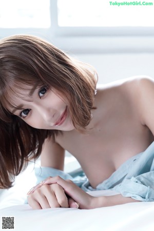 A woman in a blue bra laying on a white surface.