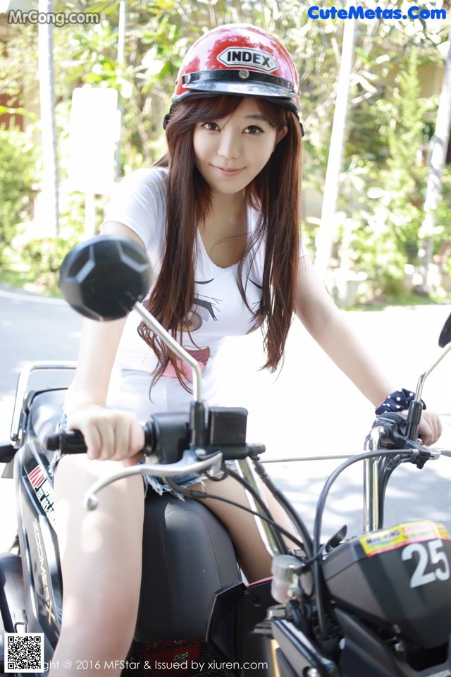 A woman wearing a helmet is sitting on a motorcycle.