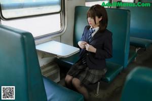 A woman in a school uniform is sitting on a train.