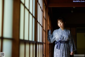 A woman in a blue and white kimono posing for a picture.