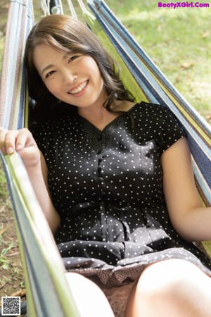 A naked asian woman laying on a bed with a pink sheet.