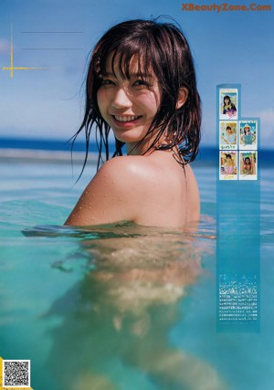 A woman in a blue bikini standing on a beach.