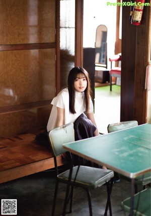 A woman with long black hair wearing a white shirt.