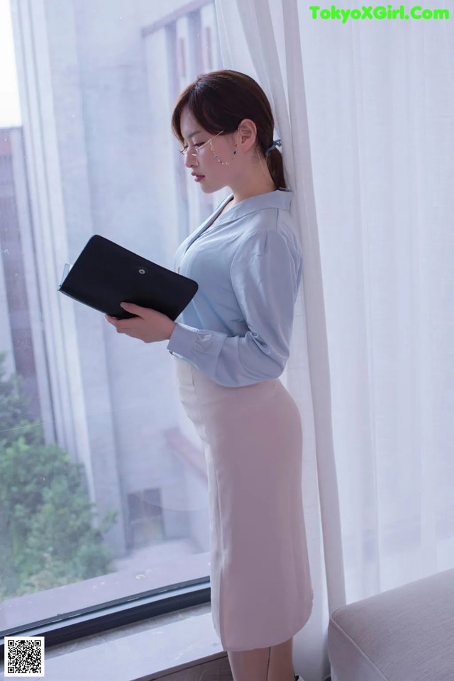 a woman standing in front of a window holding a tablet