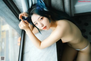 A woman with blue hair wearing a cat ears headband.