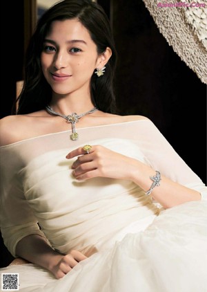 A woman wearing a white shirt and a diamond ring.