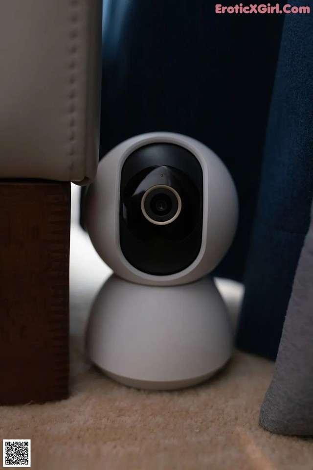 A white camera sitting on top of a carpeted floor.