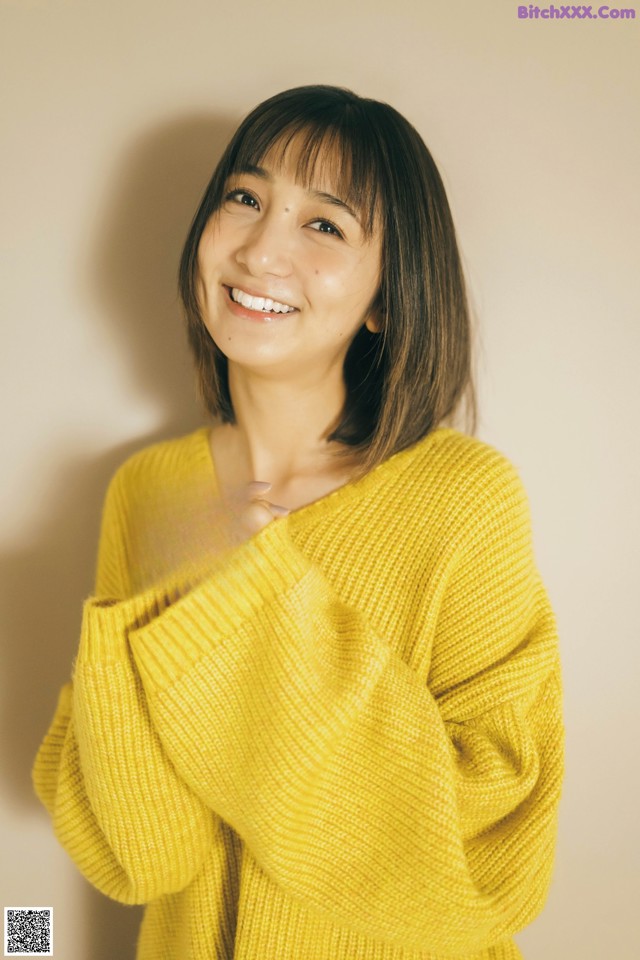 A woman in a yellow sweater smiles at the camera.