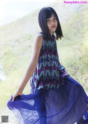 A young woman wearing a blue skirt and a colorful top.