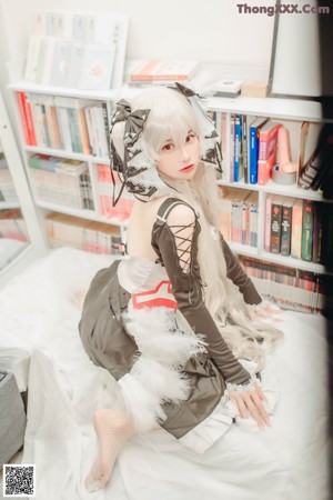 A woman in a black and white dress sitting in front of a book shelf.