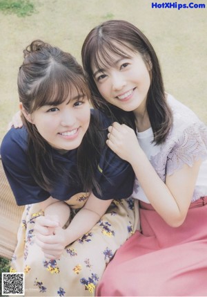 A couple of young women kneeling down in a field.