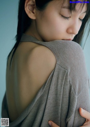 A woman with long black hair wearing a blue sweater.