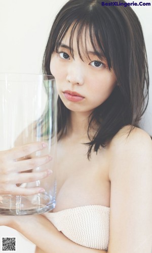 A woman in a white bikini is pouring water into a glass.