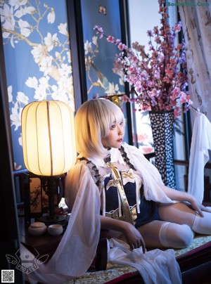 A woman sitting on top of a table next to a lamp.