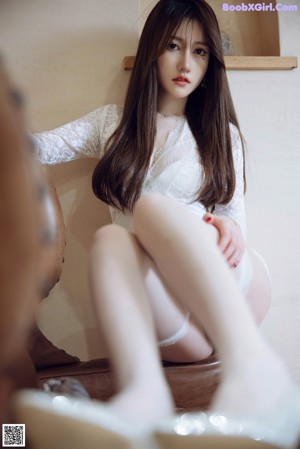 A woman sitting on a brown leather chair wearing white stockings.