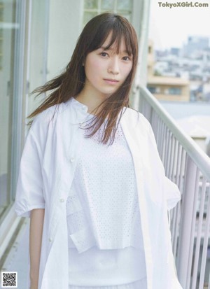 A woman with long brown hair wearing a white shirt.