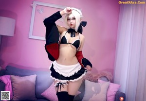 A woman in a maid outfit posing on a bed.