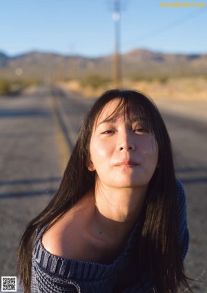 A woman laying on a log in the desert.