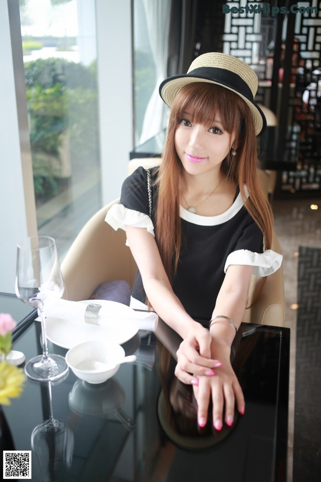 A woman sitting at a table with a hat on.