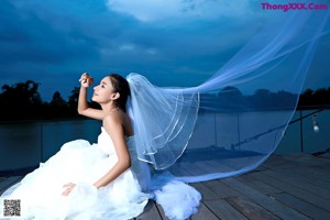 A woman in a wedding dress standing on a dock.