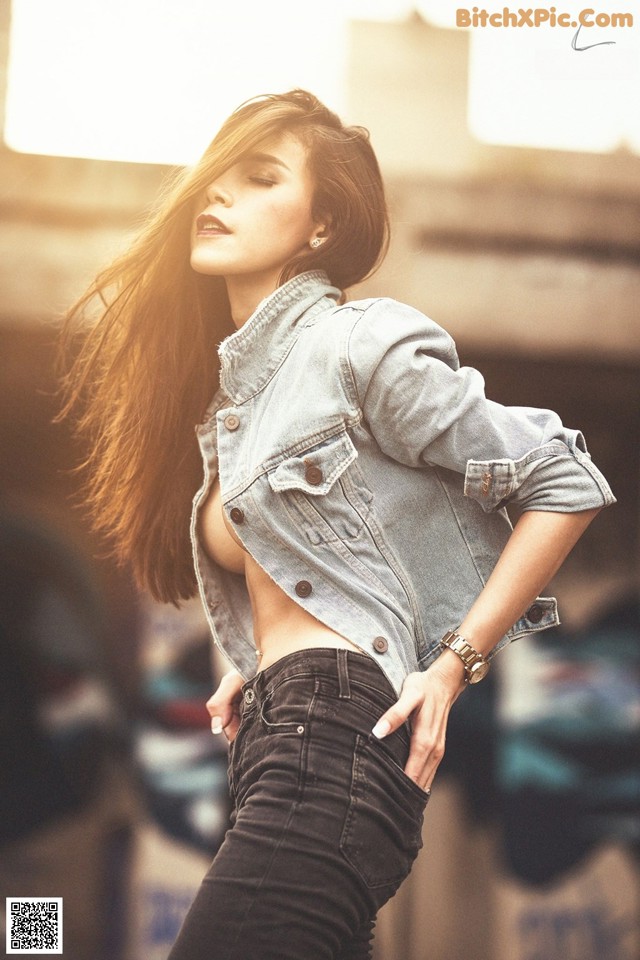 A woman in a denim jacket and jeans posing for a picture.
