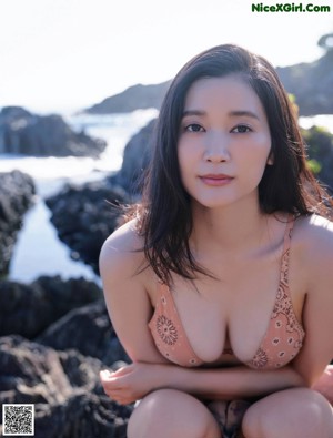 A woman in a pink bikini standing on a beach.